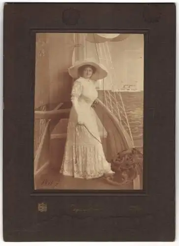 Fotografie Ateleir Helios, Detmold, edle junge Frau im weissen Sommerkleid posiert in einer Studiokulisse auf Segelboot