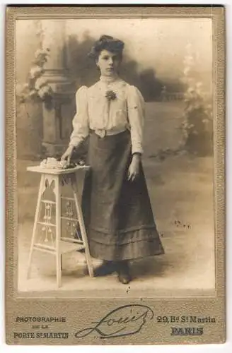 Fotografie Atelier Louis, Paris, 29 Bd. St-Martin, Junge Frau in weisser Bluse und dunklem Rock mit einem Strauss Blumen