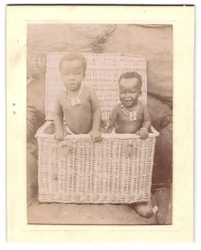 Fotografie unbekannter Fotograf und Ort, zwei afrikanische Kinder in einem Weidenkorb asl Versandgut