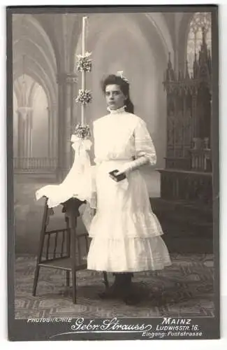 Fotografie Gebr. Strauss, Mainz, Ludwigstr. 16, junges Mädchen am Konfirmationstag im weissen Kleid mit langer Kerze