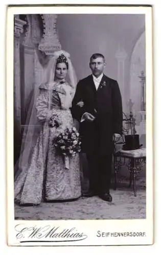 Fotografie E. W. Matthais, Seifhennersdorf, sächsisches Hochzeitspaar im verzierten Hochzeitskleid und im Anzug