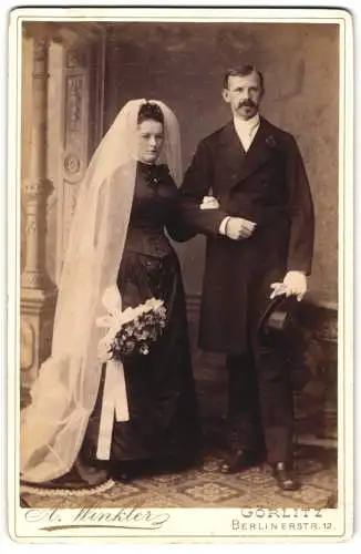 Fotografie A. Winkler, Görlitz, Berlinerstr. 12, Ehepaar am Hochzeitstag im schwarzen Brautkleid und Anzug mit Zylinder