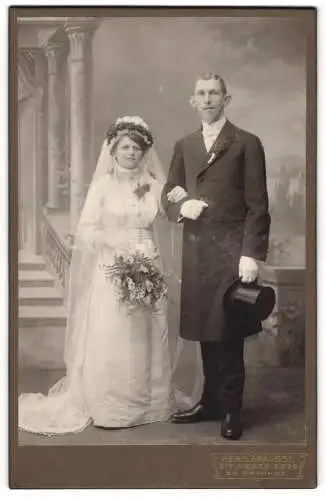 Fotografie Herm. Krausse, Steinbach i. Erz., am Bahnhof, Ehepaar im Hochzeitskleid und Anzug mit Zylinder