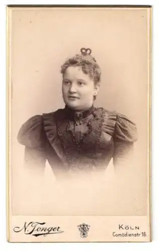 Fotografie N. Tonger, Köln a. Rh., Comödienstr. 16, junge Frau im verzierten Kleid mit Brosche