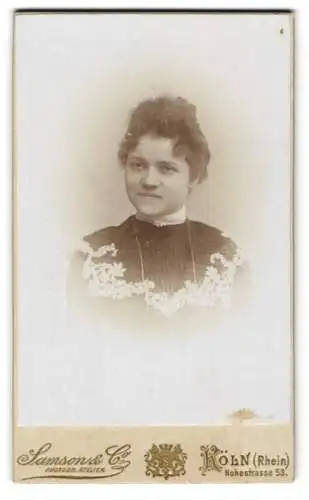 Fotografie Samsons & Co., Köln a. Rh., Hohestr. 53, Portrait junge Dame im bestickten Kleid mit Locken