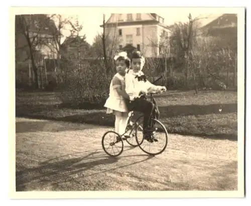 Fotografie Knabe und Mädchen fahren gemeinsam auf Dreirad