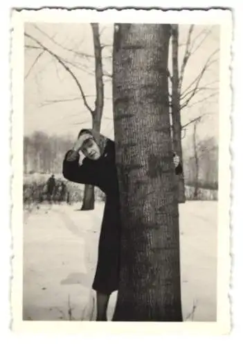 Fotografie Hausfrau hinter einem Baum hält Ausschau