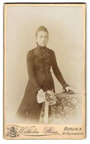 Fotografie Wilhelm Stein, Berlin, Chausseestr. 66, Elegante junge Frau mit Buch und Blumenstrauss in den Händen