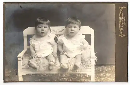 Fotografie Fried. Müller, Buchs, zwei niedliche Kinder in weissen Kleidchen sitzend auf einer Bank