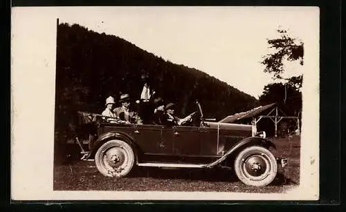 AK Auto, Ausflügler im Fahrzeug mit offenem Verdeck auf einer Wiese