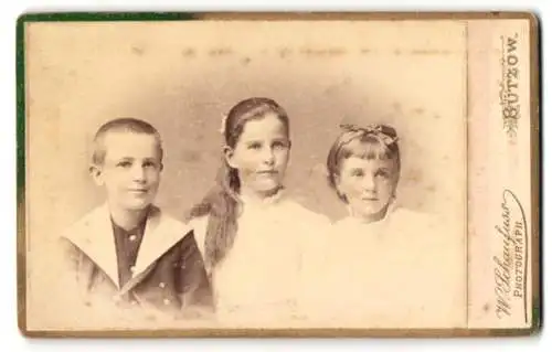 Fotografie W. Schaufuss, Bützow, Wollweber-Str. 235, Junge mit kurzem Haar und Matrosenkostüm mit seinen zwei Schwestern