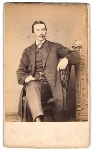 Fotografie J. Thomas, Liverpool, 66 St. Anne Street, Eleganter Herr mit Mantel, sitzend