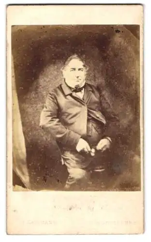 Fotografie J. Batemann, Canterbury, 54 St. Georges St., Älterer Herr in Anzug und Fliege, sitzend