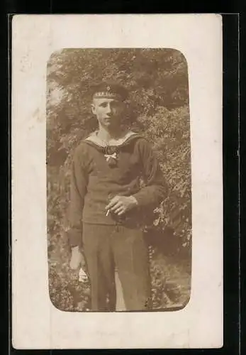 Foto-AK Junger Matrose in Uniform, Mützenband mit SMS Karlsruhe