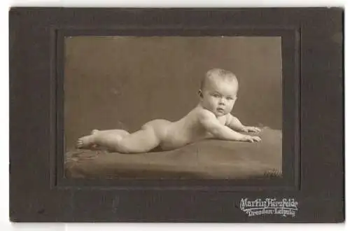 Fotografie Martin Herzfelde, Dresden, Süsses nacktes Baby mit blonden Haaren auf einer dunklen Decke