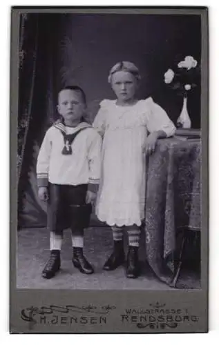 Fotografie H. Jensen, Rendsburg, Wallstr. 1, Kleiner Junge im Matrosenanzug und Mädchen im Kleid