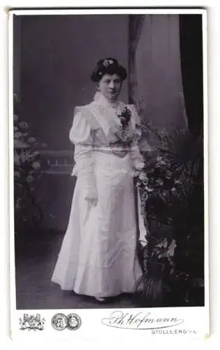 Fotografie Ph. Hofmann, Stollberg i. S., Elegante Dame in weissem Kleid mit Blumenstrauss