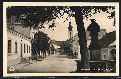 AK Münzbach /O. Ö., Strassenpartie mit Brunnendenkmal, Tordurchgang und Kirchturm