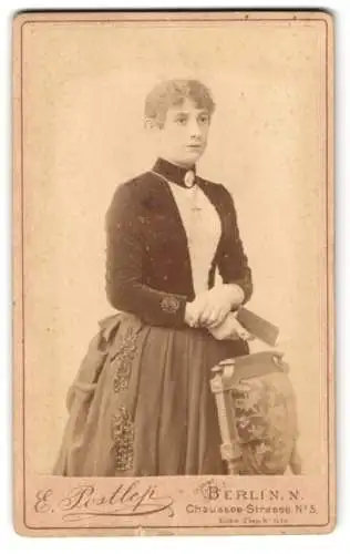 Fotografie E. Postlep, Berlin, Chausseestrasse 5, Elegante junge Dame in tailliertem Kleid mit Buch in der Hand