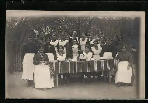 Foto-AK Dienstmädchen in Schürzen an gedecktem Tisch, Gruppenfoto