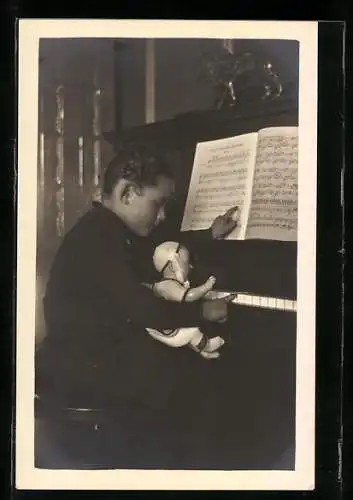 AK Knabe gibt einer Puppe Klavierunterricht