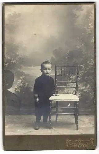 Fotografie Otto Busam, Oberkirch, Niedlicher kleiner Junge an Stuhl stehend