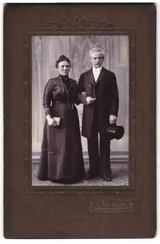 Fotografie E. Naumann, Meerane i. S., Älteres Ehepaar mit Buch und Zylinder