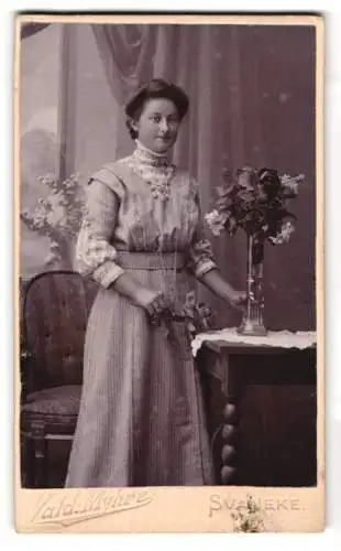 Fotografie Vald. Myhre, Svaneke, Elegante Dame in gestreiftem Kleid mit Blumenvase