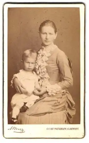 Fotografie Alois Beer, Klagenfurt, Mutter in tailliertem Kleid mit Kind auf dem Schoss
