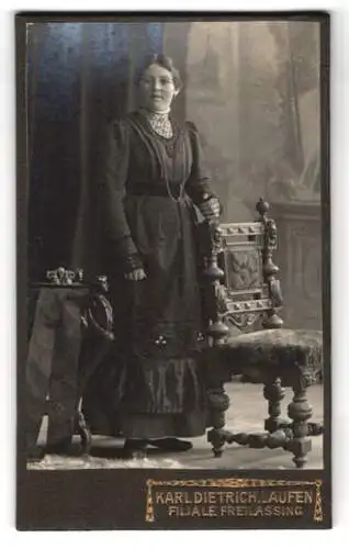 Fotografie K. Dietrich, Laufen /Salzach, Elegante Dame in hochgeschlossenem Kleid hinter Stuhl stehend