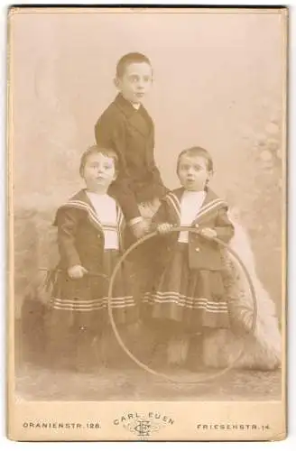 Fotografie Carl Euen, Berlin, Oranien-Str. 128 Ecke Elexandrinen-Str., Drei modisch gekleidete Kinder mit Reifen
