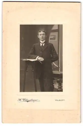 Fotografie H. Ottenstreuer, Velbert, Junger Herr mit Mittelscheitel und Krawatte an einem Hochtischchen