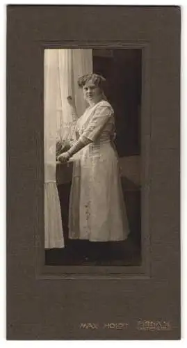 Fotografie Max Holdt, Pirna /A. E., Garten-Str. 31, Blonde Dame mit ondulierten Haaren im weissen Kleid an einem Fenster