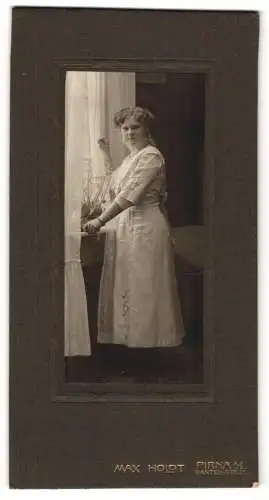 Fotografie Max Holdt, Pirna /A. E., Garten-Str. 31, Blonde junge Dame mit Armband im weissen Kleid an einem Fenster
