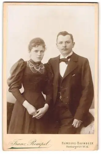 Fotografie Franz Rompel, Hamburg-Barmbeck, Hamburgerstrasse 54 /56, Ernstes junges Paar in Puffärmelkleid und Dreiteiler