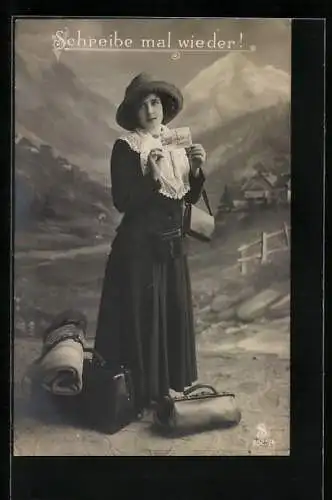 AK Schreibe mal wieder!, schönes Fräulein präsentiert neben ihrem Gepäck eine Ansichtskarte, Gebirgs-Studokulisse
