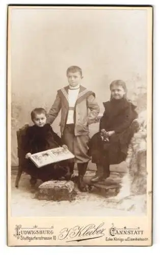 Fotografie J. Kleiber, Ludwigsburg, Stuttgarterstrasse 10, Drei niedliche Geschwister mit aufgeschlagenem Buch