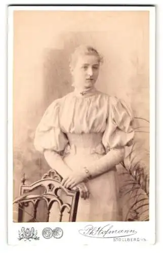 Fotografie Ph. Hofmann, Stollberg i. S., Am Bahnhof, Elegante junge Dame in hochgeschlossenem Kleid mit Schleifen