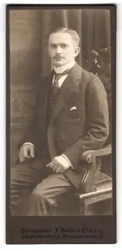 Fotografie J. Fuchs & Co., Charlottenburg, Wilmersdorfer Str. 57, Sitzender junger Mann mit gemusterter Krawatte