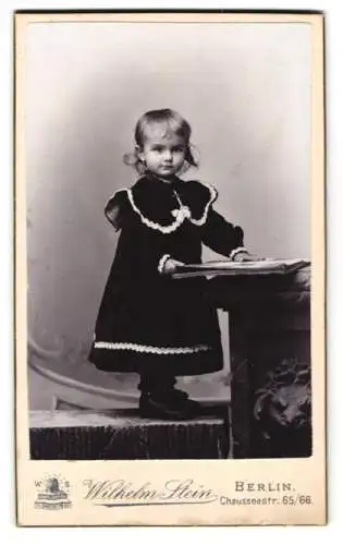 Fotografie Wilhelm Stein, Berlin, Chausseestr. 65, Süsses kleines Mädchen in schwarzem Kleid mit Fotoalbum
