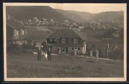 Foto-AK Bad Harzburg, Eltern mit Kind vor dem Haus Am Butterberg 8, mit Blick auf den Ort, 1926