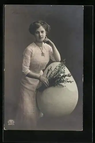 Foto-AK R & K / L Nr. 4697/1: Junge Dame lehnt sich an ein riesiges Osterei