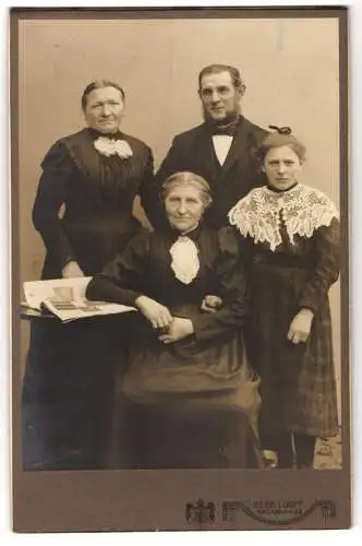 Fotografie Gebr. Looff, Dresden, Saalhausenerstr. 15, Gutbürgerliche Familie in eleganter schwarzer Kleidung mit Zeitung