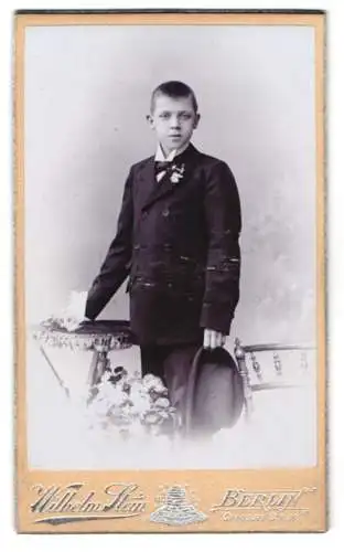 Fotografie Wilhelm Stein, Berlin, Chaussee-Str. 66, Junge in elegantem Anzug mit Hut in der Hand