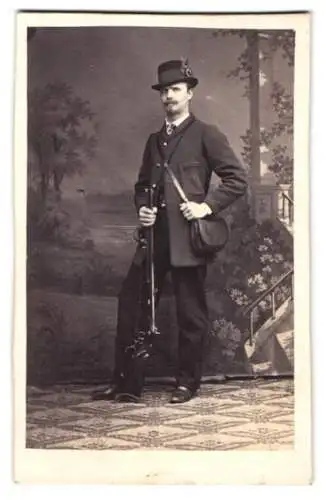 Fotografie A. Breuning, Hanau, Jäger mit Flinte und Schwarzpulvertasche vor einer Studiokulisse