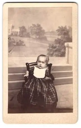 Fotografie A. Breuning, Hanau, niedliches kleines Mädchen im karierten Kleid vor einer Studiokulisse