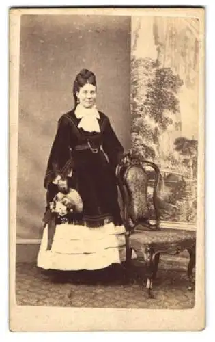 Fotografie unbekannter Fotograf und Ort, Dame im hellen Kleid mit dunklem Überwurf und Sommerhut in der Hand