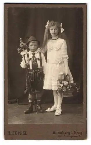 Fotografie H. Föppel, Annaberg i. Erzg., junger Knabe in Tracht mit Lederhose nebst Schwester als Blumenmädchen