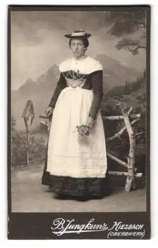 Fotografie B. Junghans, Miesbach, junge Frau im Trachtenkleid vor einer Studiokulisse