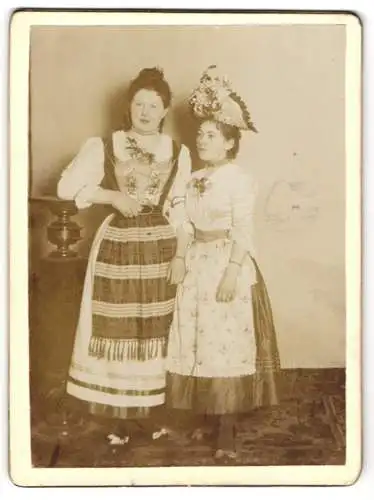 Fotografie unbekannter Fotograf und Ort, zwei junge Frauen im Trachtenkleid und mit geschmücktem Hut zum Fasching
